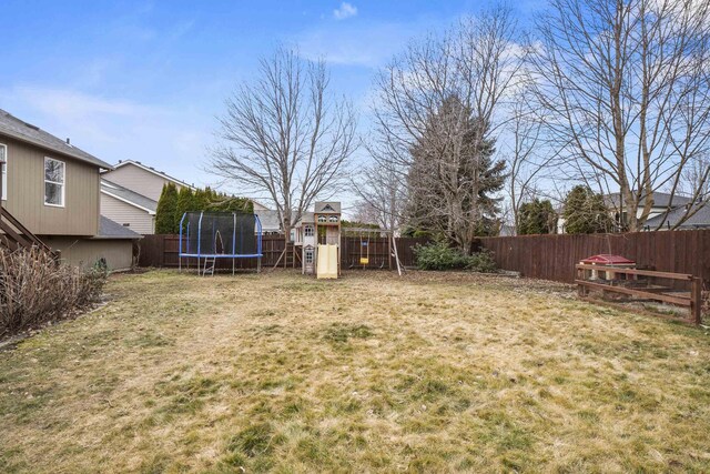 view of yard featuring a trampoline, a fenced backyard, and a playground