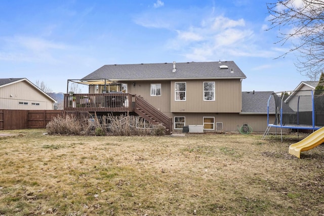 back of property featuring stairway, fence, a wooden deck, a playground, and a trampoline