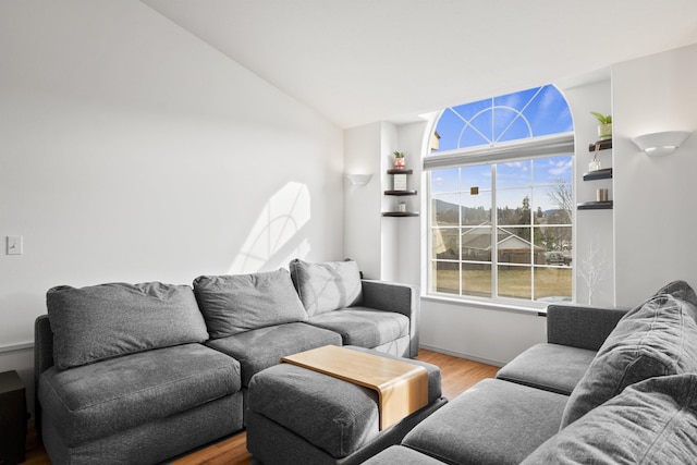 living area featuring vaulted ceiling, wood finished floors, and baseboards