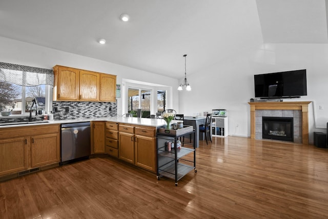 kitchen featuring a sink, stainless steel dishwasher, light countertops, and vaulted ceiling