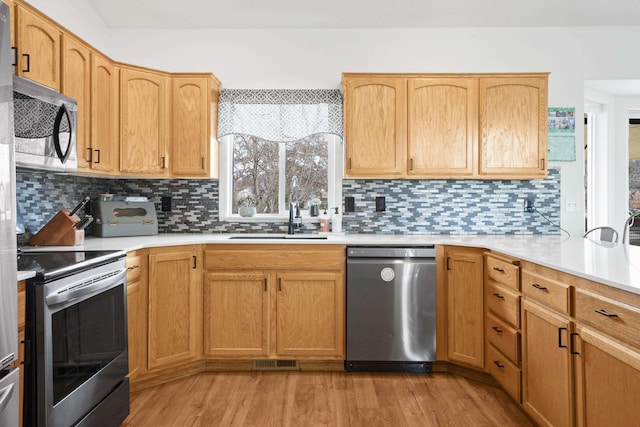 kitchen featuring light wood finished floors, visible vents, light countertops, stainless steel appliances, and a sink