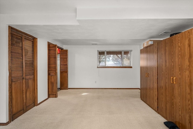 unfurnished bedroom with visible vents, light colored carpet, two closets, and baseboards