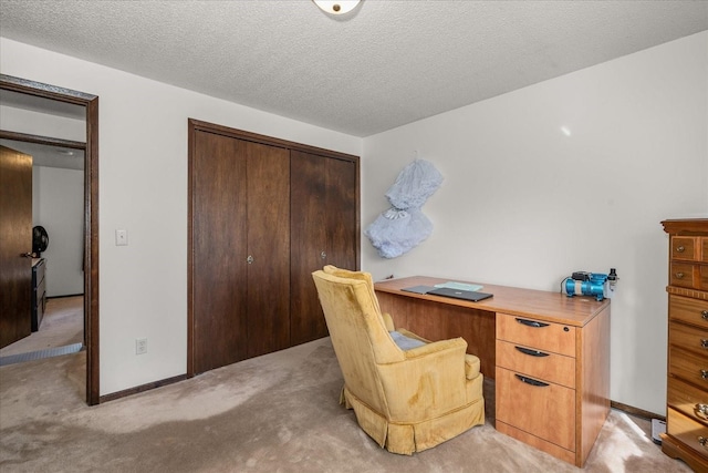 office space featuring light colored carpet, baseboards, and a textured ceiling