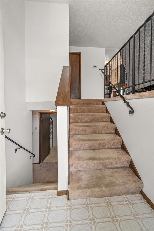 stairs featuring a textured ceiling