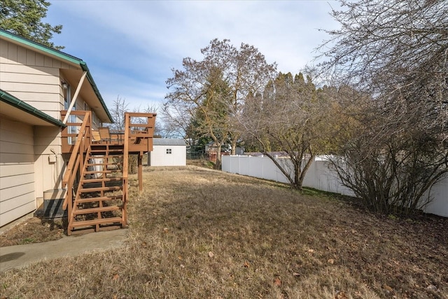 view of yard with an outbuilding, stairway, a wooden deck, and fence