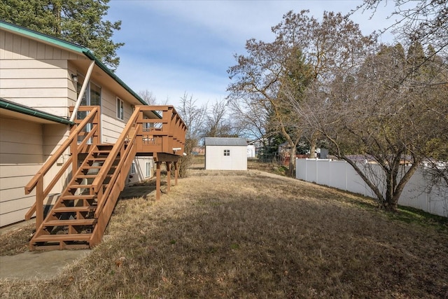 view of yard with fence, a shed, stairs, a deck, and an outdoor structure