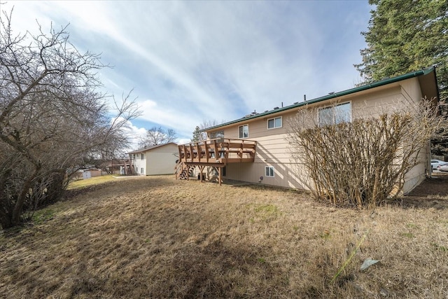 rear view of property with a wooden deck, a lawn, and stairway