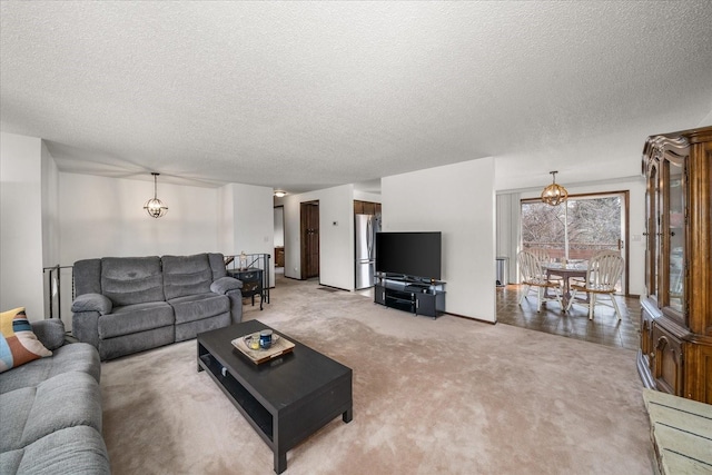 living area featuring a chandelier, light colored carpet, and a textured ceiling