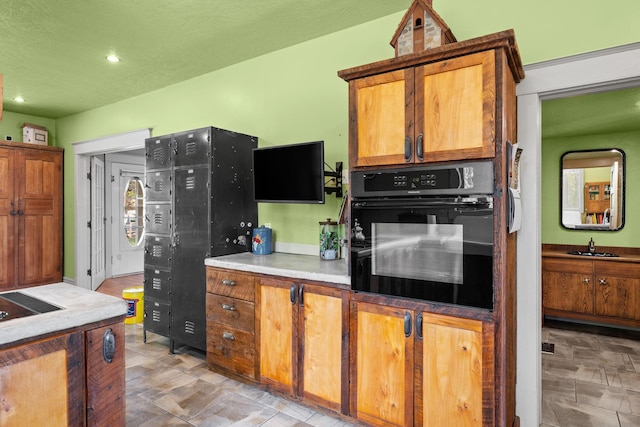 kitchen with recessed lighting, brown cabinets, dobule oven black, and a sink