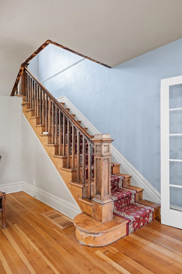 staircase featuring visible vents, baseboards, and hardwood / wood-style floors