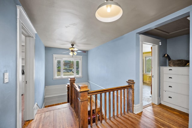 hall with a wainscoted wall, an upstairs landing, and wood finished floors