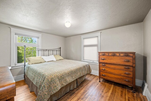 bedroom with baseboards, wood-type flooring, and a textured ceiling