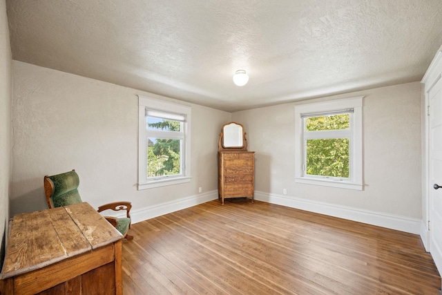 sitting room with a textured ceiling, baseboards, and hardwood / wood-style floors