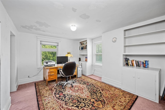 carpeted office featuring baseboards, built in shelves, and plenty of natural light