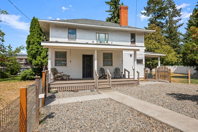 american foursquare style home with fence, covered porch, and a chimney