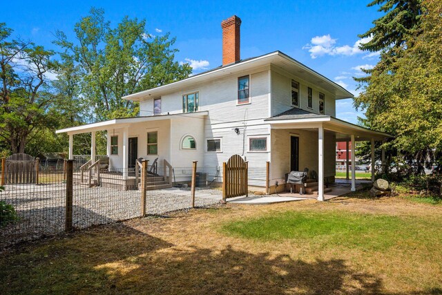 back of property with a lawn, a gate, fence, a chimney, and a patio area