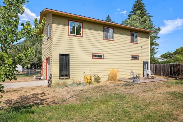 rear view of property with a patio area, a yard, fence, and concrete driveway