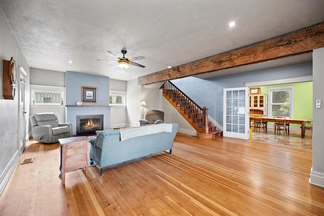 living area with a healthy amount of sunlight, light wood-type flooring, stairs, and baseboards