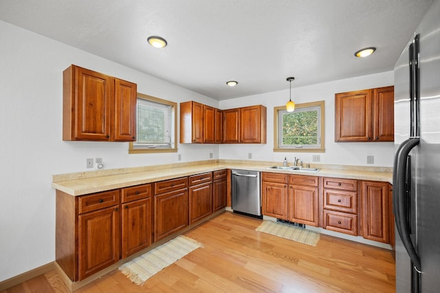 kitchen with brown cabinets, appliances with stainless steel finishes, light wood-type flooring, and a sink