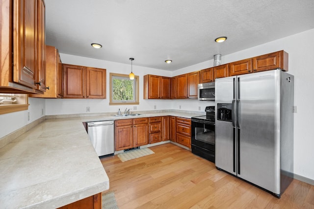 kitchen with brown cabinetry, stainless steel appliances, light countertops, and a sink