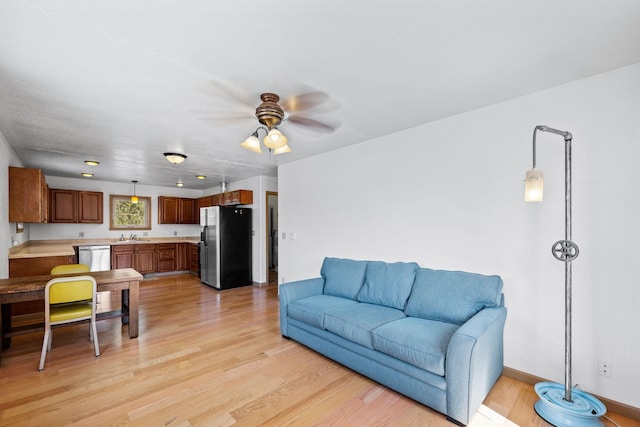 living area with baseboards, a ceiling fan, and light wood-style floors