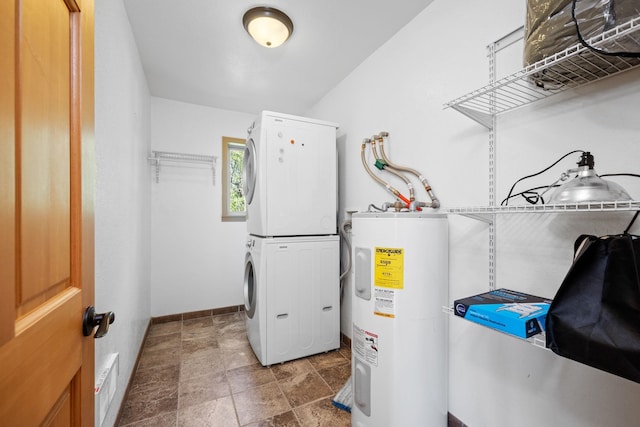 clothes washing area with visible vents, electric water heater, stacked washing maching and dryer, baseboards, and laundry area