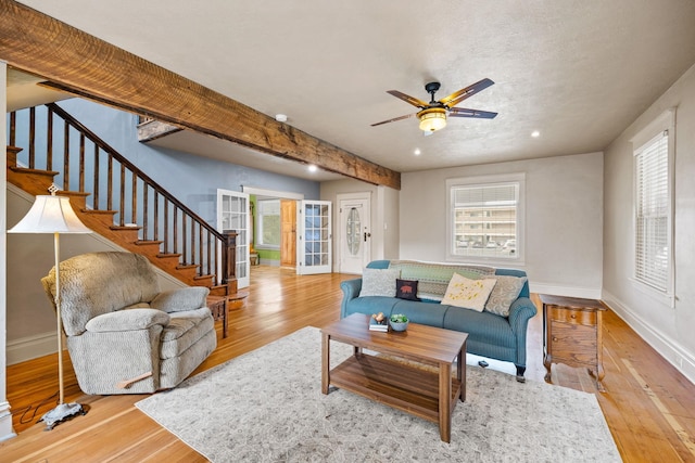 living area featuring hardwood / wood-style floors, beam ceiling, stairs, and baseboards