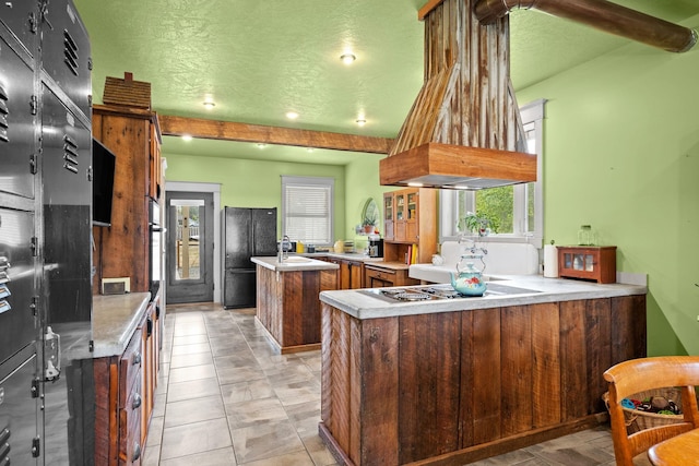 kitchen featuring a kitchen island, beam ceiling, a peninsula, freestanding refrigerator, and light countertops