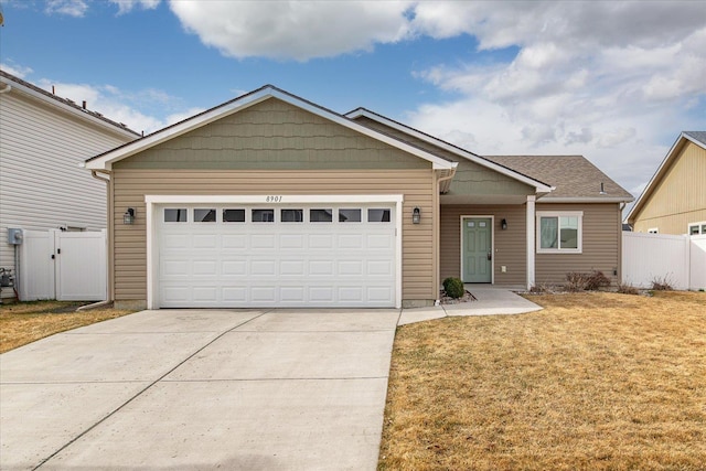 view of front facade featuring a front yard, concrete driveway, fence, and an attached garage