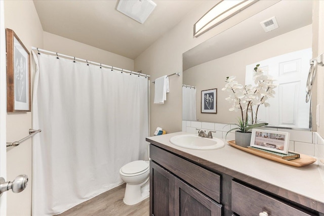 bathroom with visible vents, curtained shower, toilet, wood finished floors, and vanity