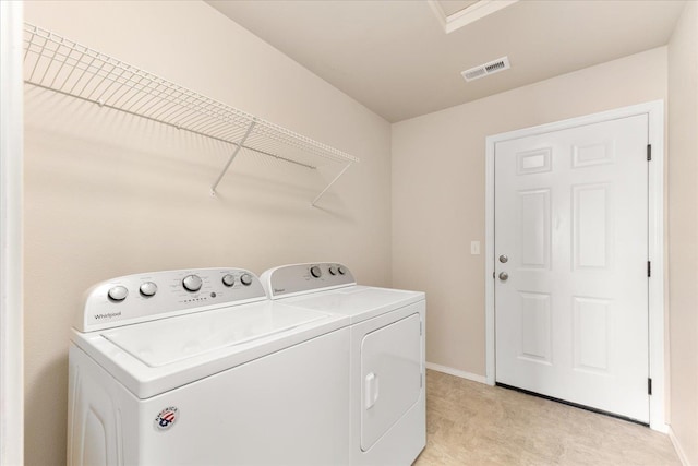 clothes washing area with visible vents, baseboards, separate washer and dryer, and laundry area