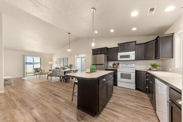 kitchen with visible vents, a sink, open floor plan, white appliances, and light countertops