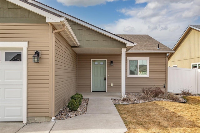 property entrance featuring fence, a garage, and a shingled roof