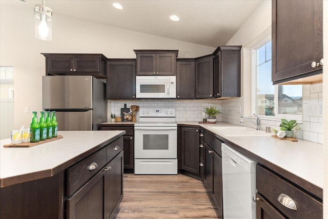 kitchen with white appliances, lofted ceiling, a sink, dark brown cabinets, and light wood-style floors