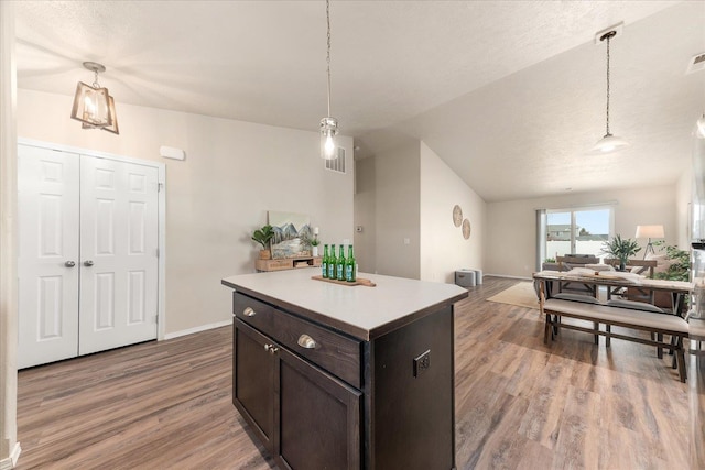 kitchen featuring light wood finished floors, decorative light fixtures, open floor plan, light countertops, and vaulted ceiling