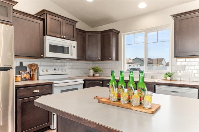 kitchen with tasteful backsplash, white appliances, dark brown cabinetry, light countertops, and lofted ceiling