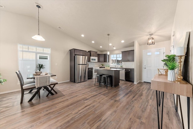 dining room with vaulted ceiling, light wood-style flooring, recessed lighting, and baseboards