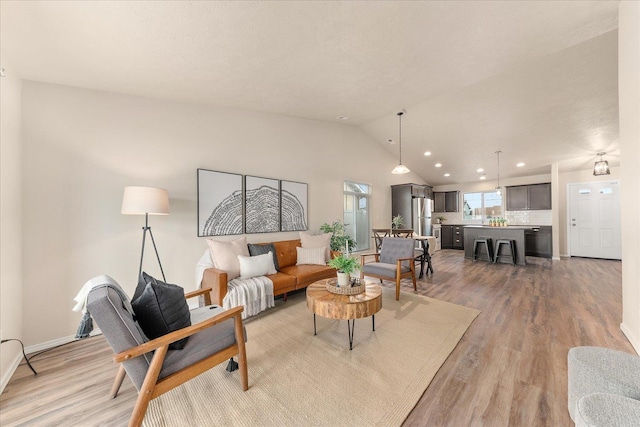 living room featuring recessed lighting, baseboards, lofted ceiling, and light wood finished floors