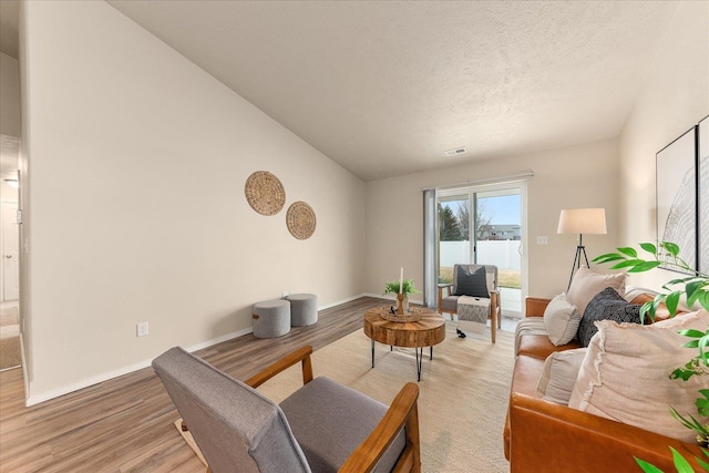 living area featuring light wood-style flooring, visible vents, baseboards, and a textured ceiling