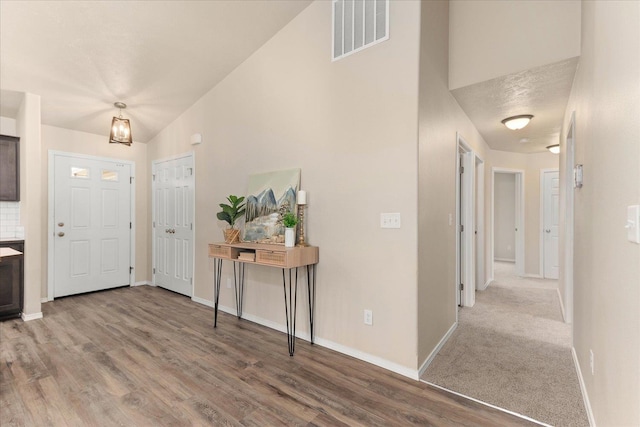 entrance foyer with wood finished floors, baseboards, visible vents, and high vaulted ceiling