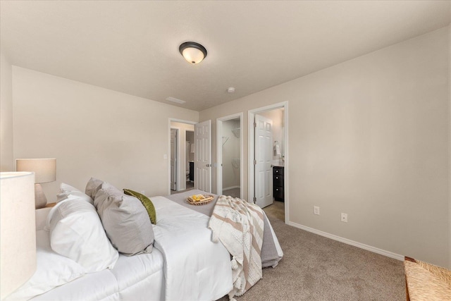 bedroom with baseboards, light carpet, and a walk in closet