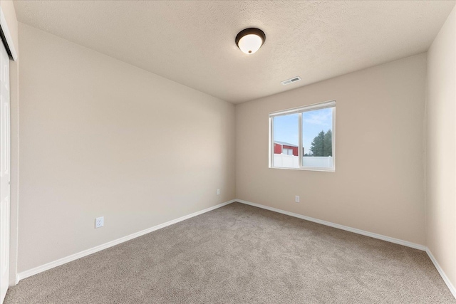 unfurnished room featuring baseboards, carpet floors, a textured ceiling, and visible vents