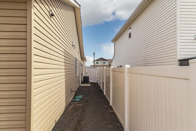 view of side of home with cooling unit and a fenced backyard