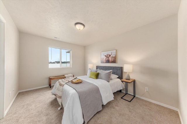 bedroom with visible vents, light carpet, a textured ceiling, and baseboards