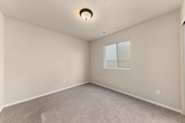 carpeted empty room featuring visible vents and baseboards