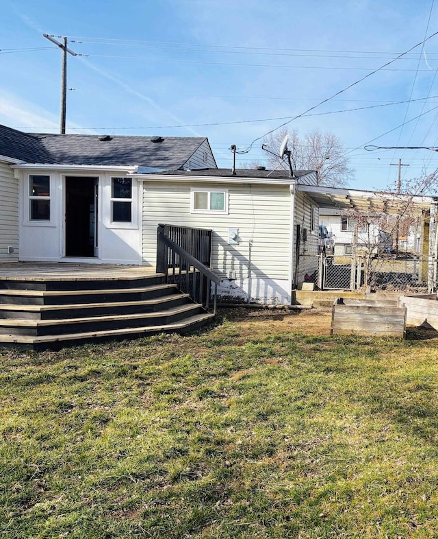 back of property with a yard, a deck, and fence