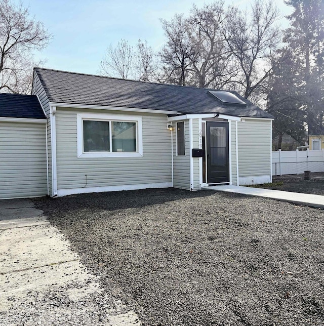 ranch-style home featuring fence and roof with shingles