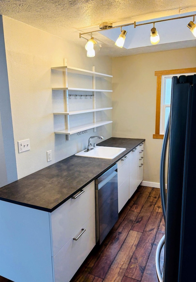 kitchen with dark wood-style flooring, freestanding refrigerator, a sink, dishwasher, and dark countertops