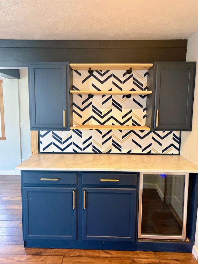 bar featuring tasteful backsplash, beverage cooler, dark wood-style flooring, and a textured ceiling