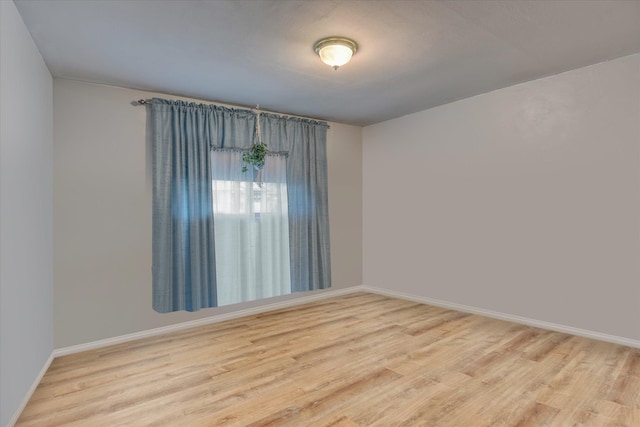 spare room with baseboards and wood finished floors